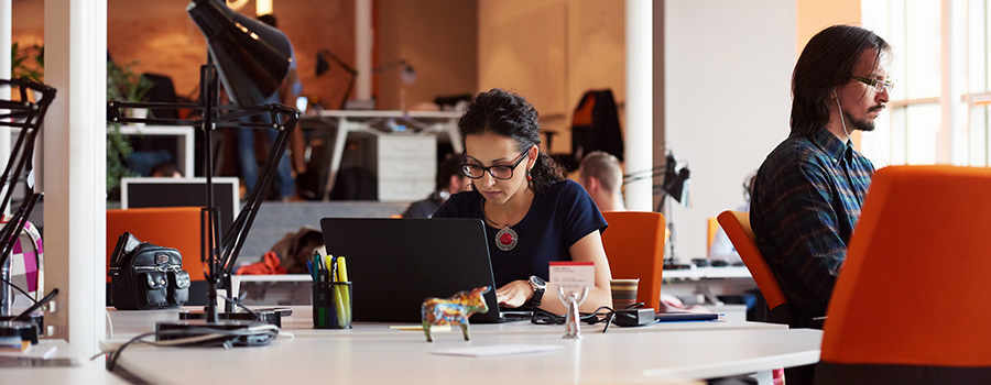 People working at desks with laptops in a modern office setting.