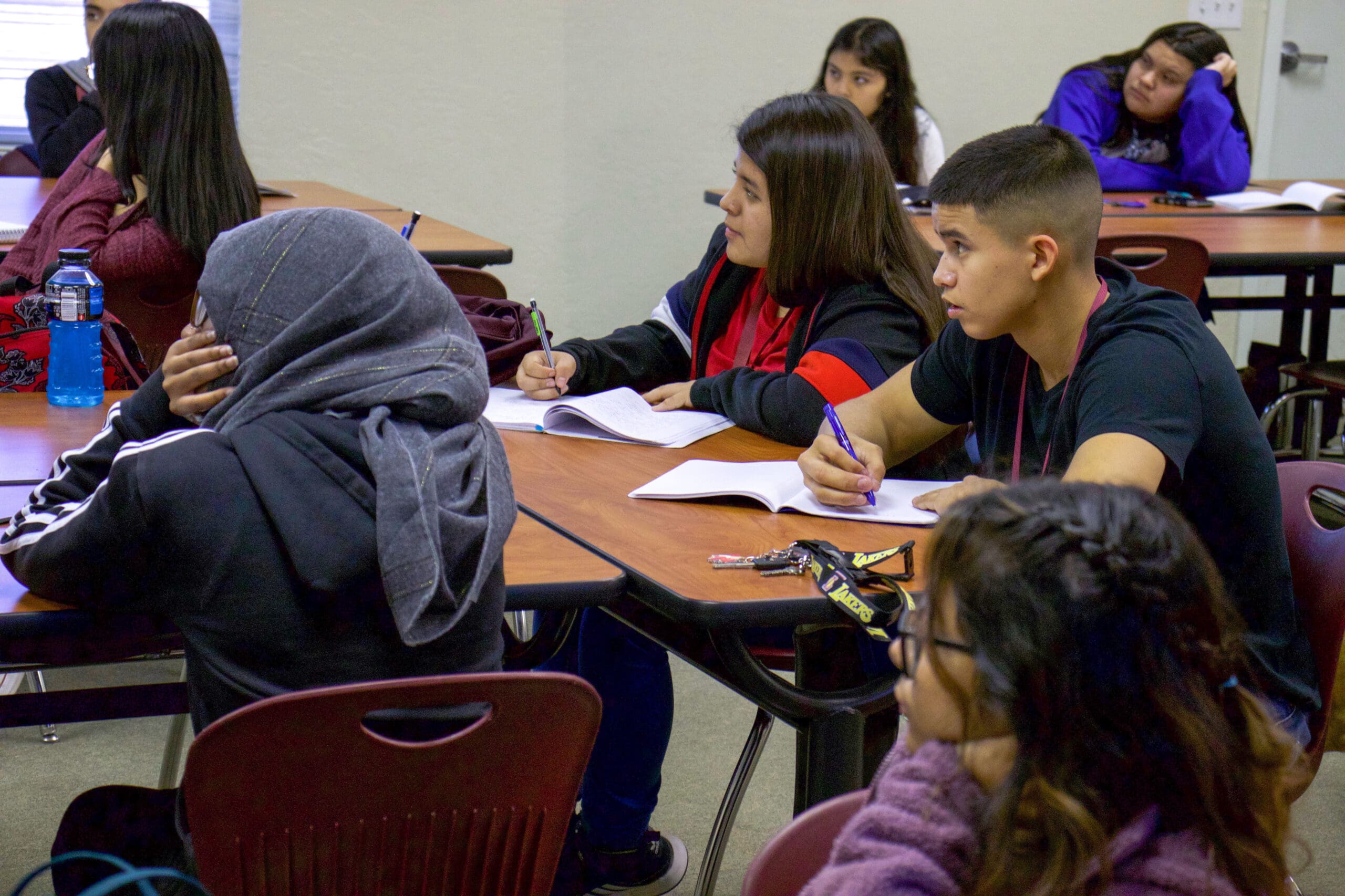 Students sitting at desks in a classroom, attentively listening and taking notes.