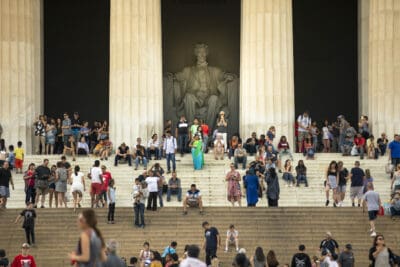 People gathered on the steps of the Lincoln Memorial, with the statue of Abraham Lincoln visible in the background.
