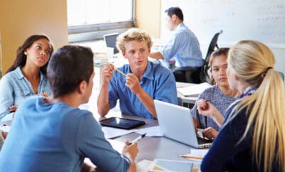 Students study together at a table in a classroom