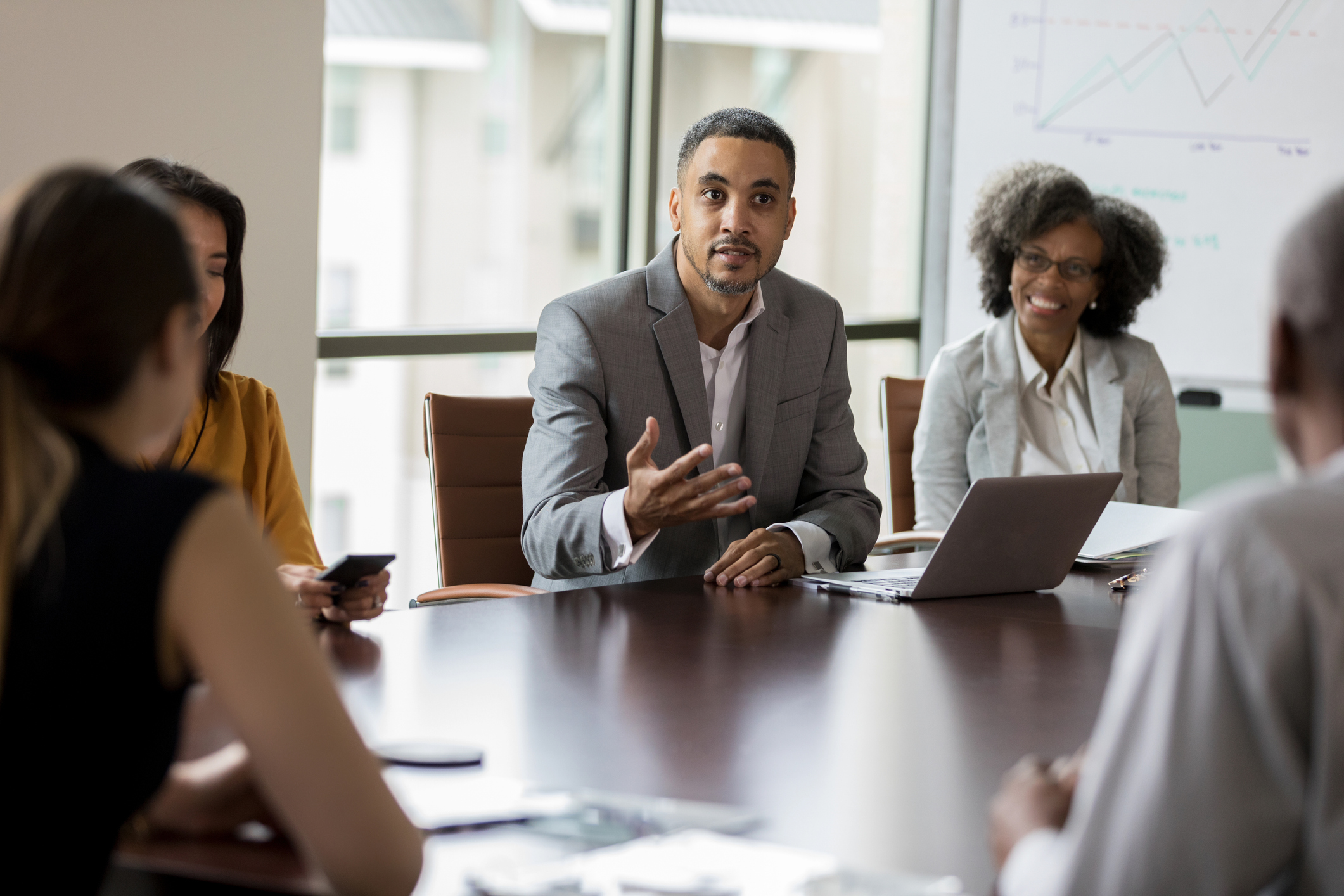 Mid adult African American businessman gestures while discussing a project with a group of associates.