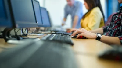 People working on computers in an office setting, focusing on typing and screen activity.