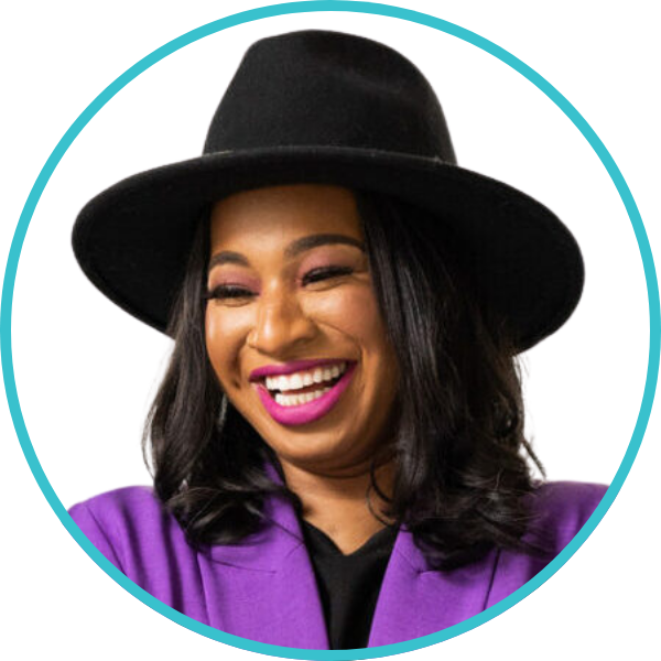 A woman with long dark hair wears a wide-brimmed black hat, a purple blazer, and bright pink lipstick, smiling against a white background.