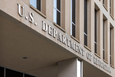 Exterior view of the U.S. Department of Education building, showing its name on the facade and large windows above.