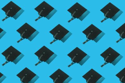 Repeating pattern of black graduation caps with tassels arranged diagonally on a bright blue background.