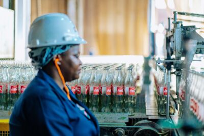 Worker Overseeing Glass Bottles on Assembly Line