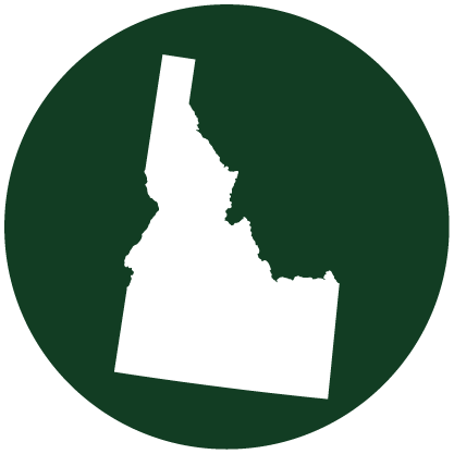 White silhouette of the state of Idaho on a dark green circular background.